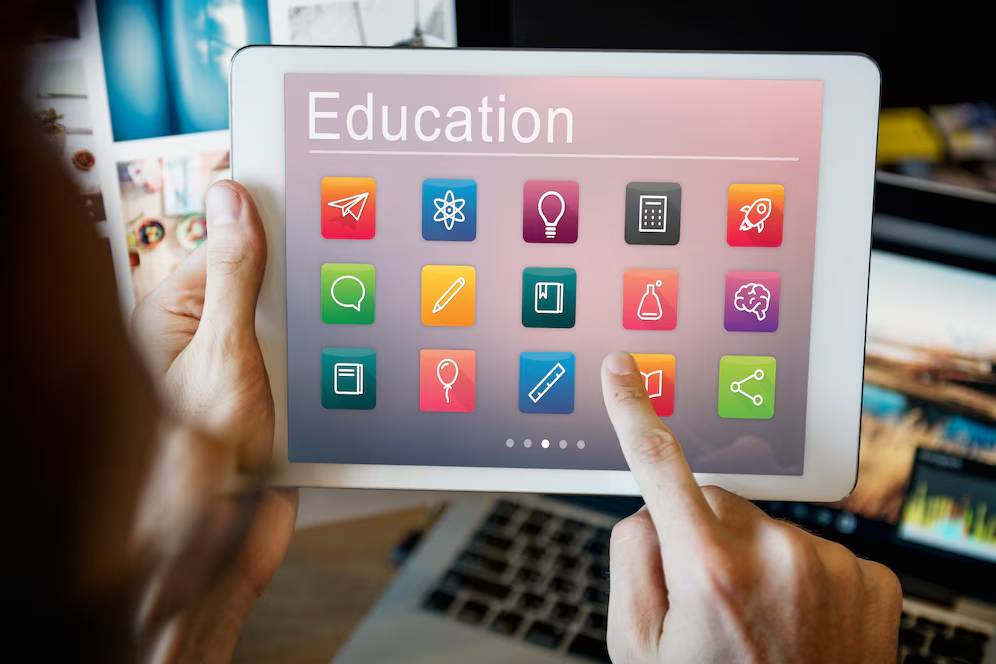 Person using a tablet with education-related app icons on the screen.
