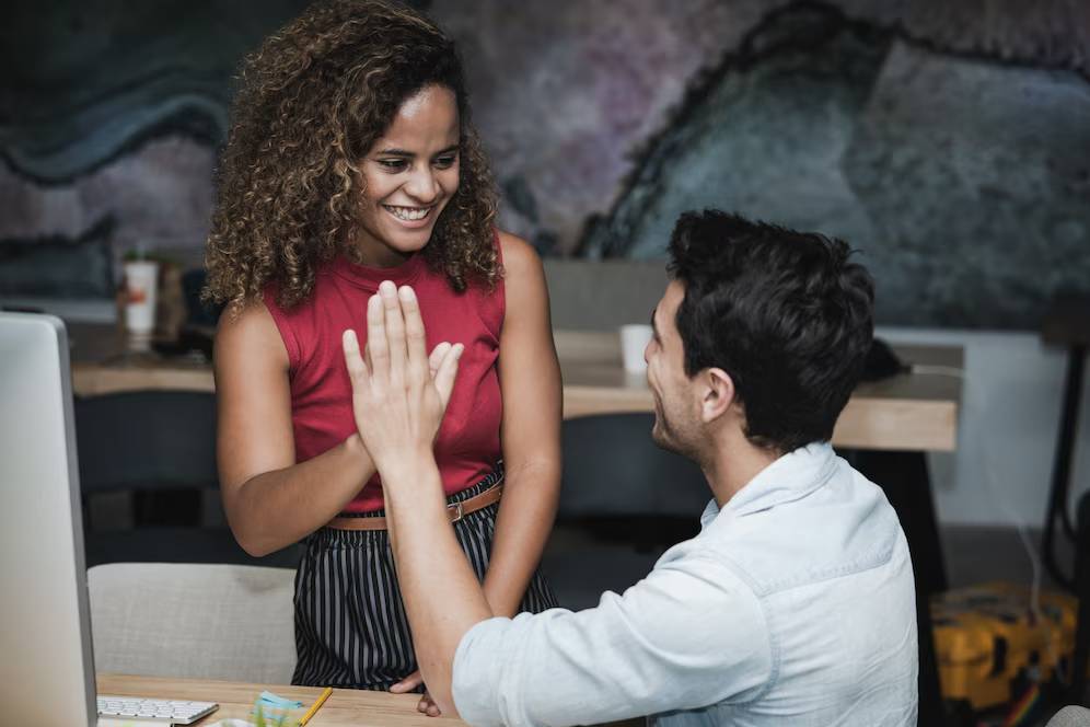 A man and woman happily engaging and high-fiving in a creative office space.