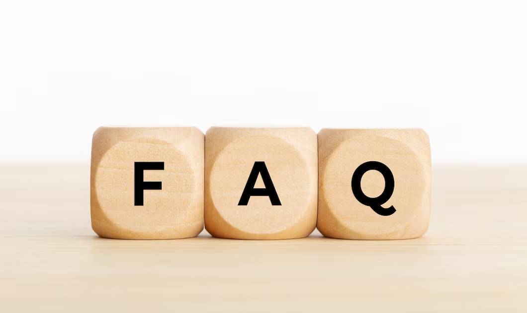 Three wooden blocks with letters F, A, Q on a table, forming the word FAQ.