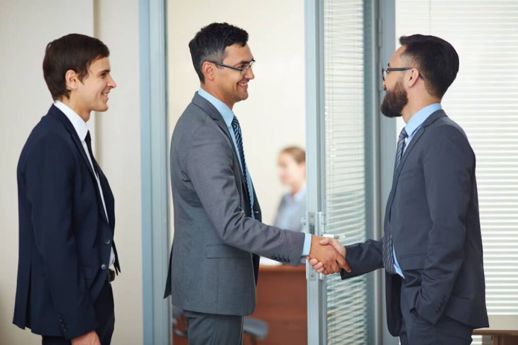 Two people in business attire shaking hands against a clear blue sky.