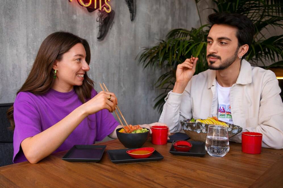 Two people enjoying a meal with sushi and salads at a restaurant table.