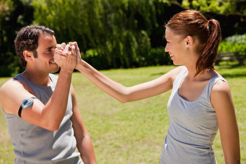 Man and woman smiling and playing in a sunny park, man looking through an improvised camera made with hands.
